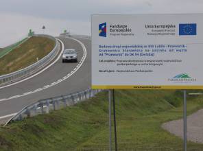 Zdjęcie przedstawia fragment nowo wybudowanej drogi oraz tablicę informującą i inwestycji